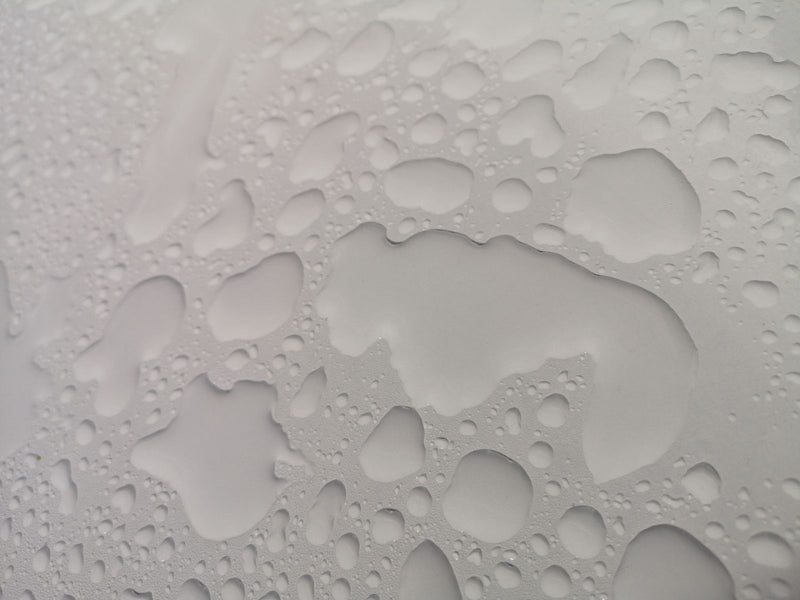 Water droplets forming patterns on a white surface