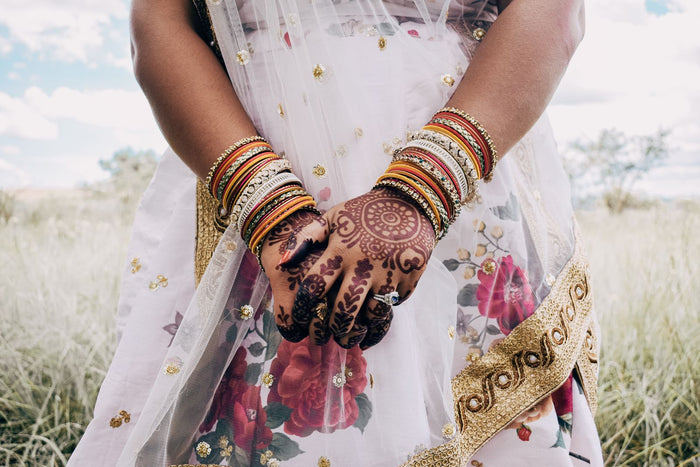 Close-up of a South Asian bride's hands with intricate mehndi and gold bangles