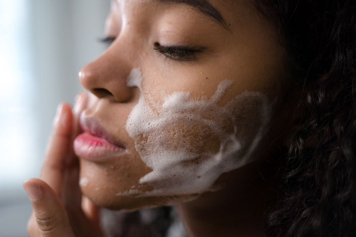 Woman gently cleansing her face with foam as part of a calming acne-friendly routine