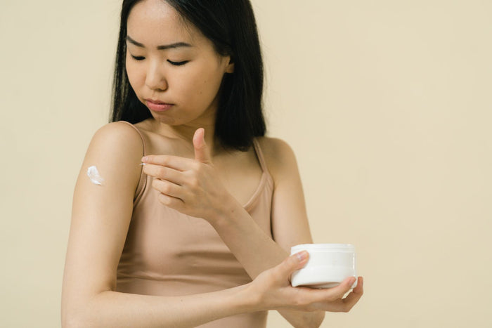 Woman applying a soothing moisturiser to her skin in warm light