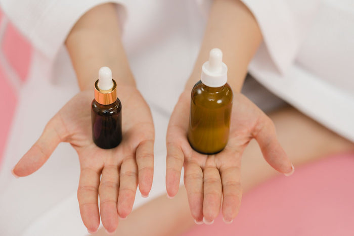 Hands holding two skincare dropper bottles
