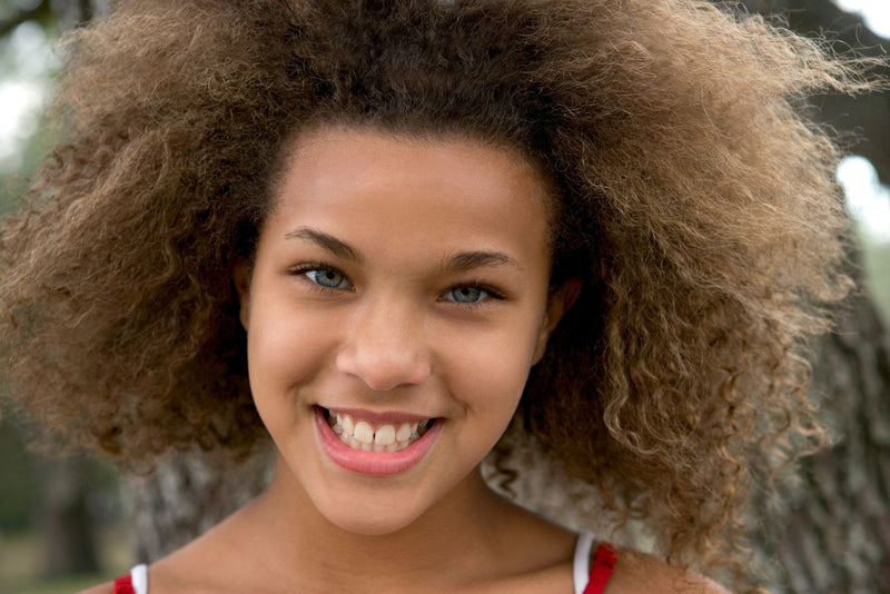 Smiling teenager with natural curls outdoors