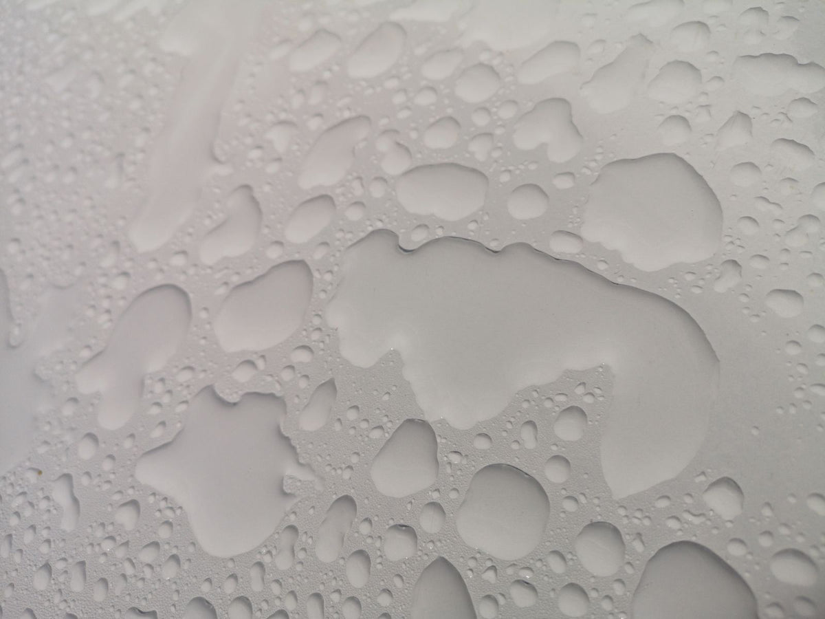 Water droplets forming patterns on a white surface