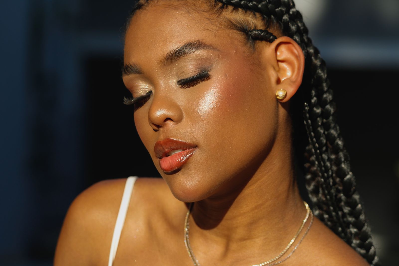 Woman with braided hair in warm sunlight, skin looking fresh and radiant