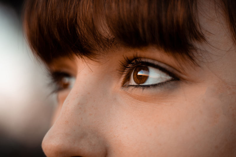 Close-up of a woman's under-eye area and brown eye in natural light