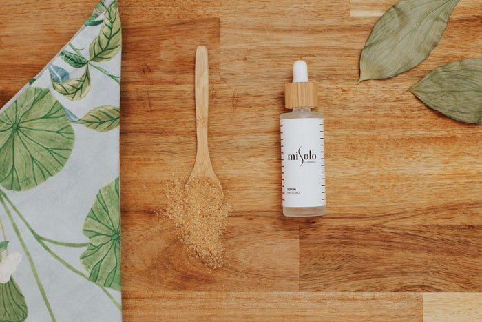 Amber serum bottle with a dropper and leaf on a warm wooden surface