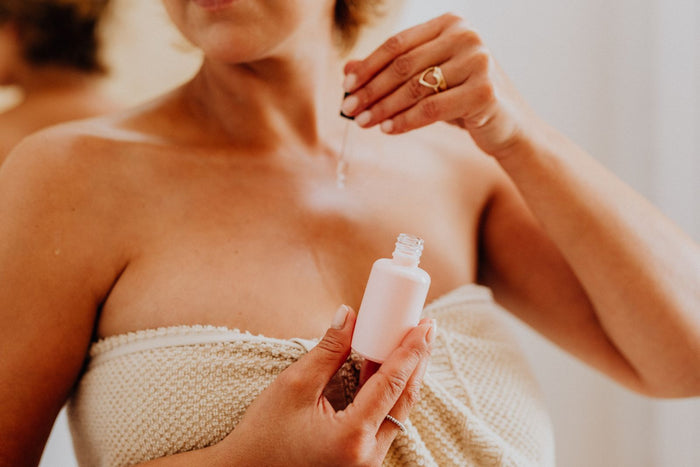 Close-up of a woman applying serum to combination skin in warm light