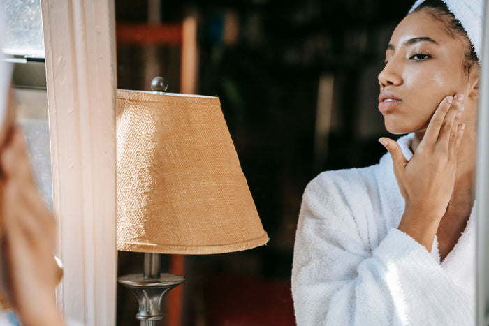 Woman touching her cheek at the mirror, checking dry or dehydrated skin
