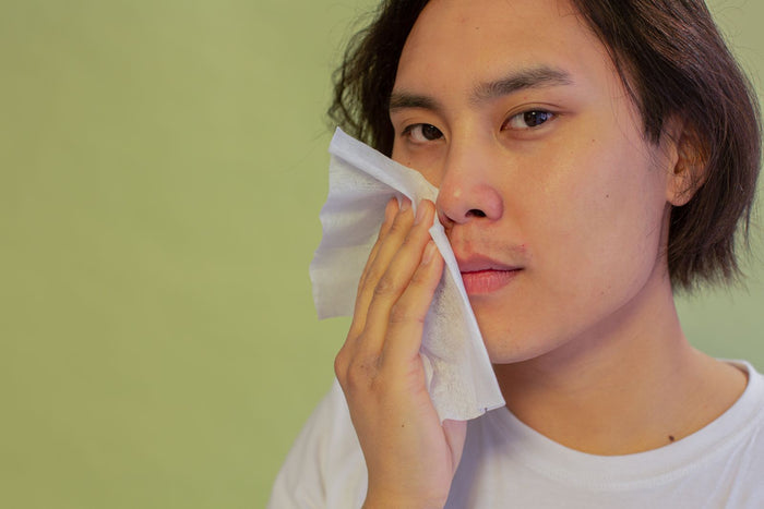 Young man with smooth skin cleansing his face