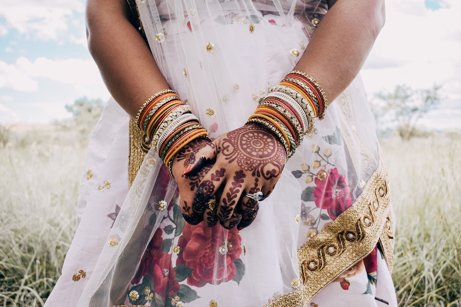 Close-up of a South Asian bride's hands with intricate mehndi and gold bangles