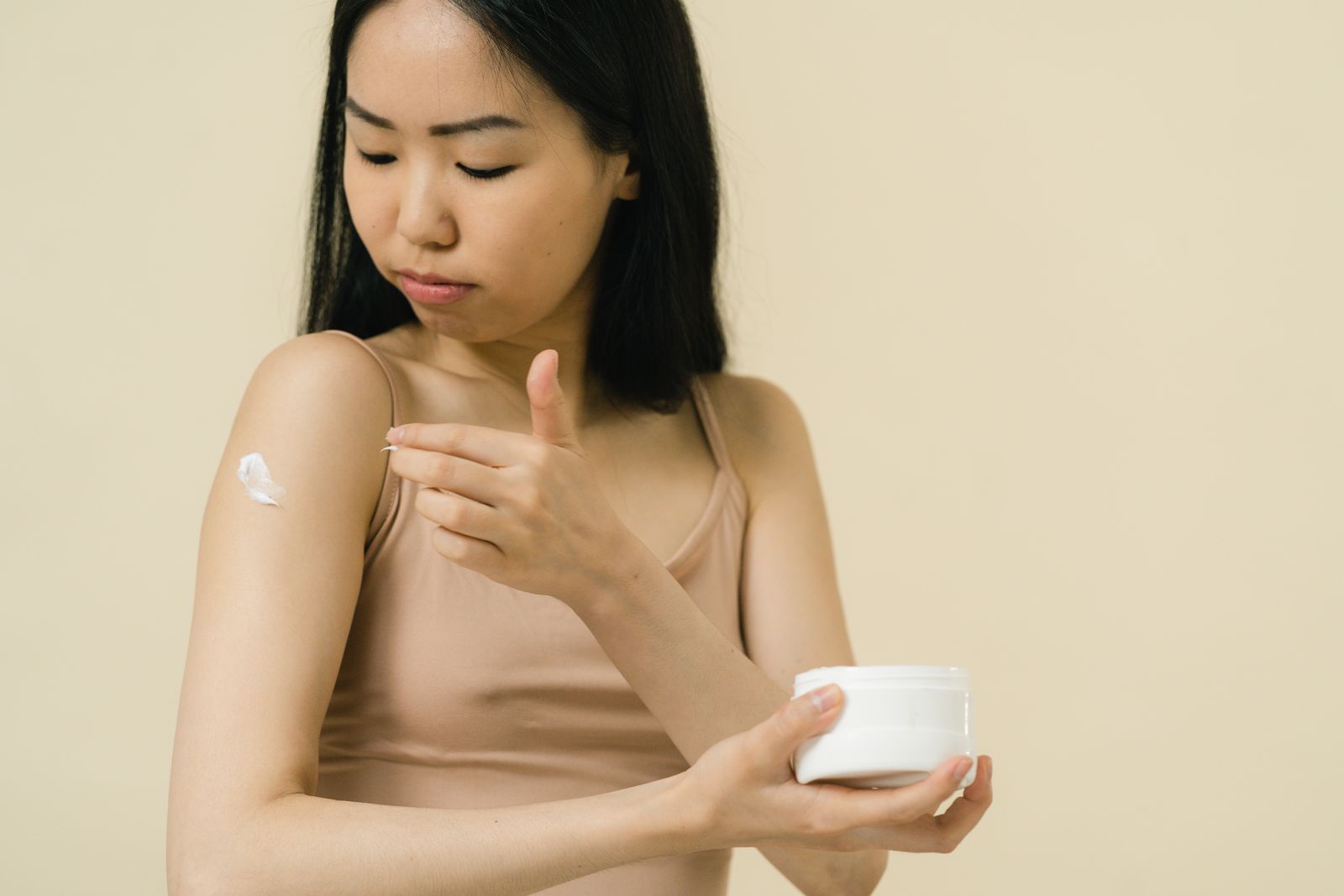 Woman applying a soothing moisturiser to her skin in warm light